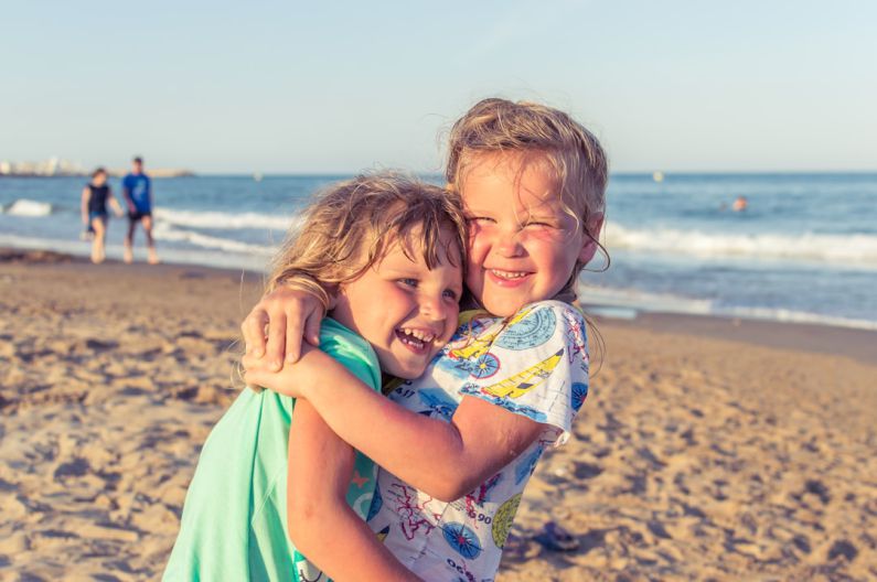 Family Fun - girl in white blue and green floral dress on beach during daytime