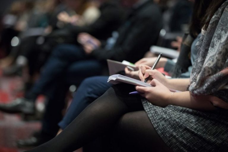 Event - selective focus photography of people sitting on chairs while writing on notebooks