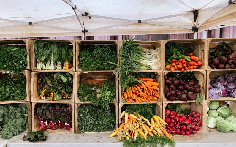 Farmers Market - a variety of vegetables are displayed in wooden crates