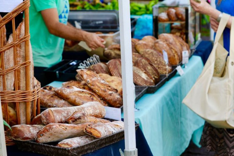 Farmers Market - person carrying beige tote bag in front of food stall at daytime