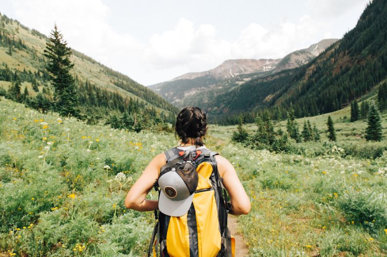 Outdoor - person carrying yellow and black backpack walking between green plants