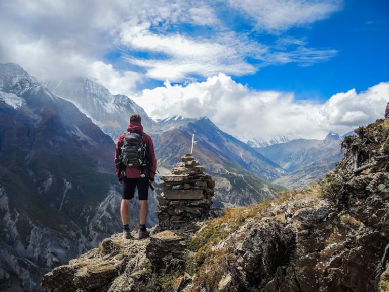 Outdoor - man standing on top of mountain beside cairn stones