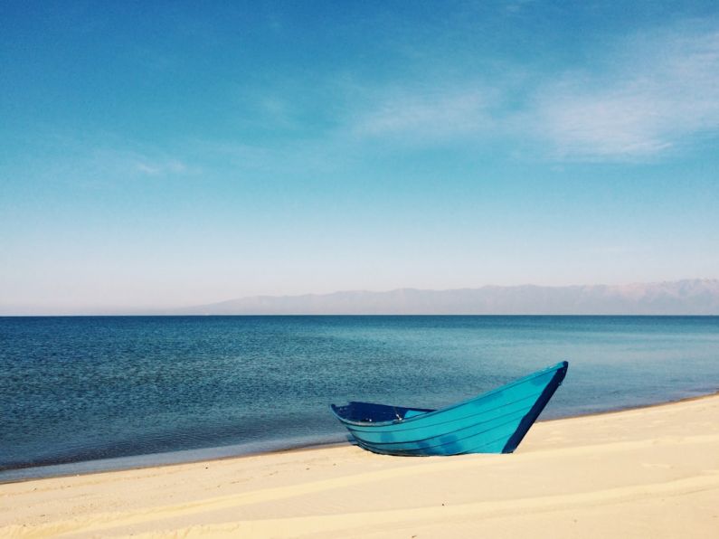 Outdoor - blue boat on sand near body of water during daytime